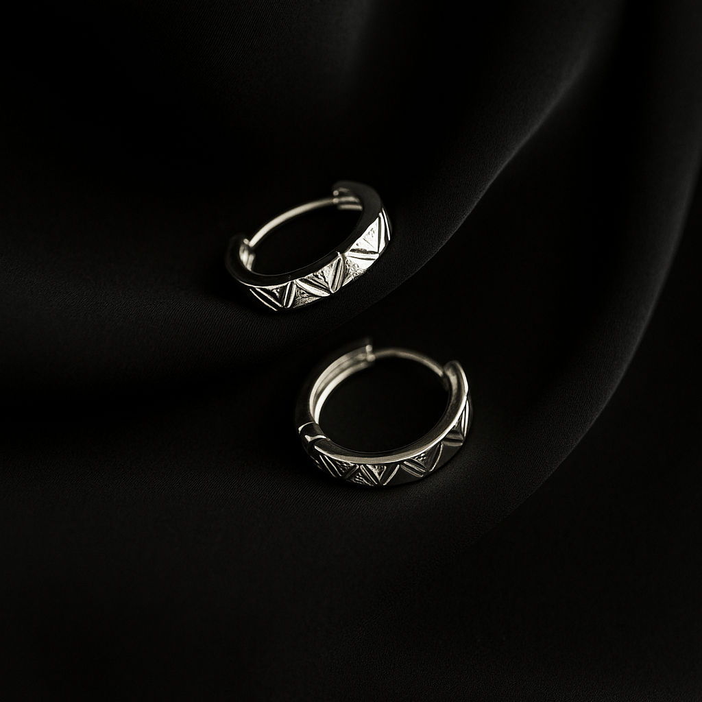 Pair of silver hoop earrings on a black fabric background