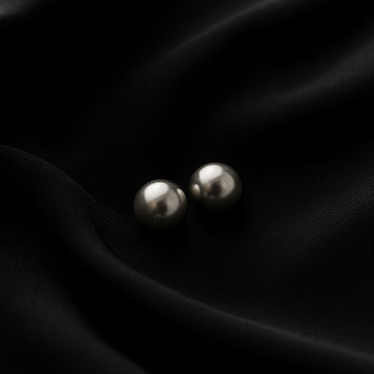 Pair of silver earrings on black satin fabric