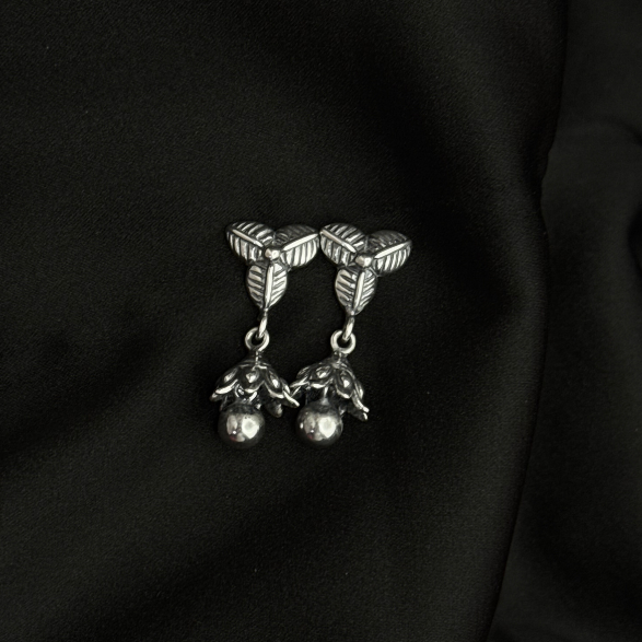 Silver brooch with leaf design on a black fabric background