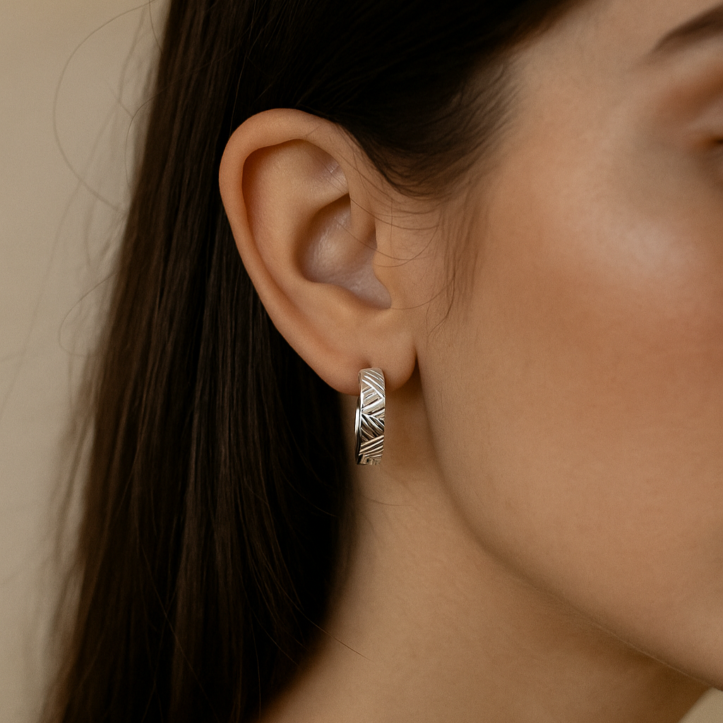 Close-up of an ear wearing a silver earring with a neutral background