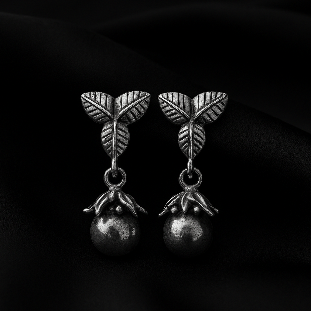 Pair of silver earrings with leaf design on a black background