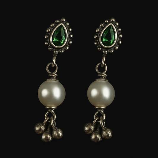 Pair of earrings with pearls and green gemstones on a black background