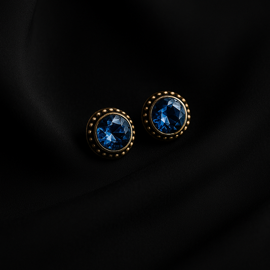 Pair of round earrings with blue gemstones on a black background