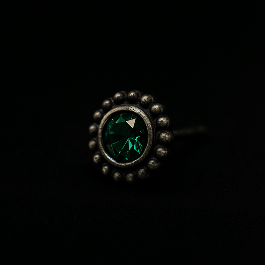 Ring with green gemstone and black stones on a black background