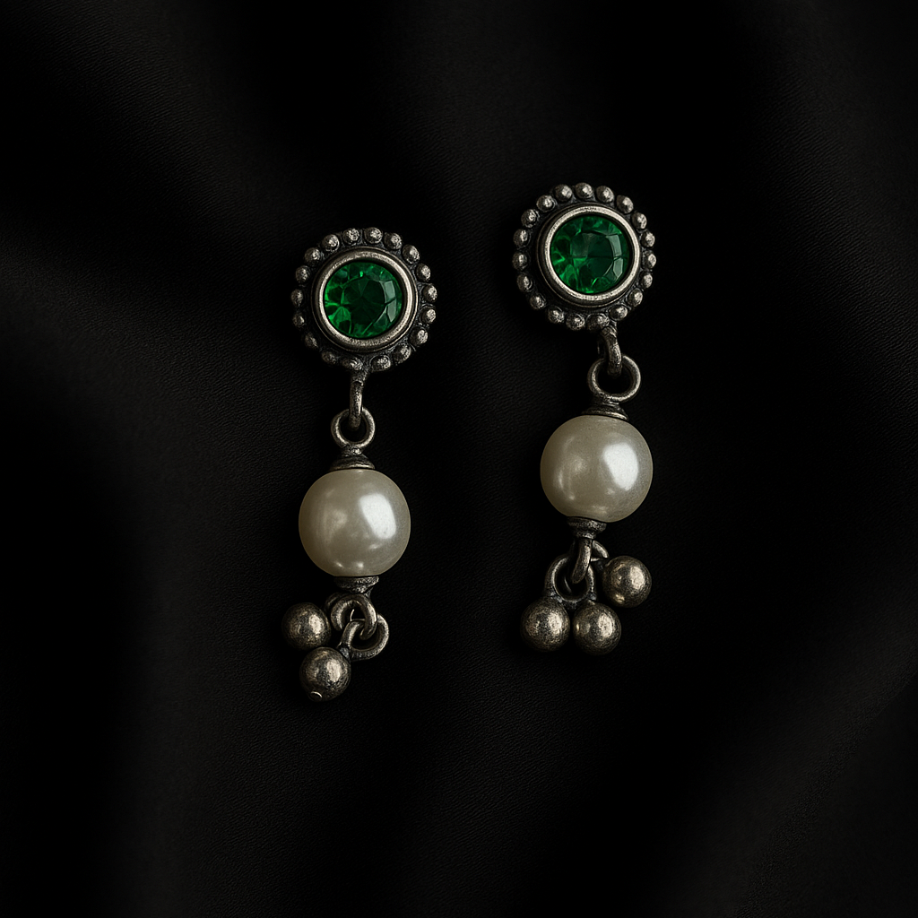Pair of earrings with pearls and green gemstones on a black background