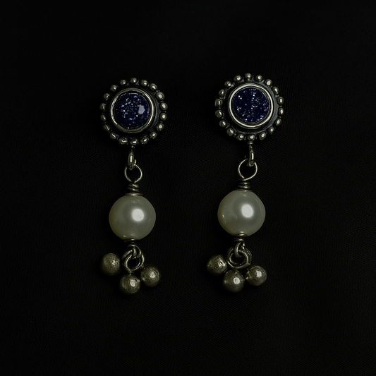Pair of earrings with pearls and gemstones on a black background