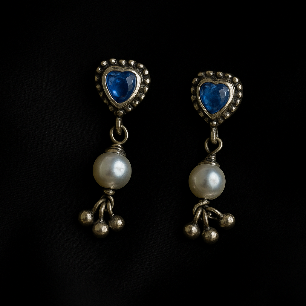 Pair of earrings with heart-shaped blue stones and pearl-like beads on a black background